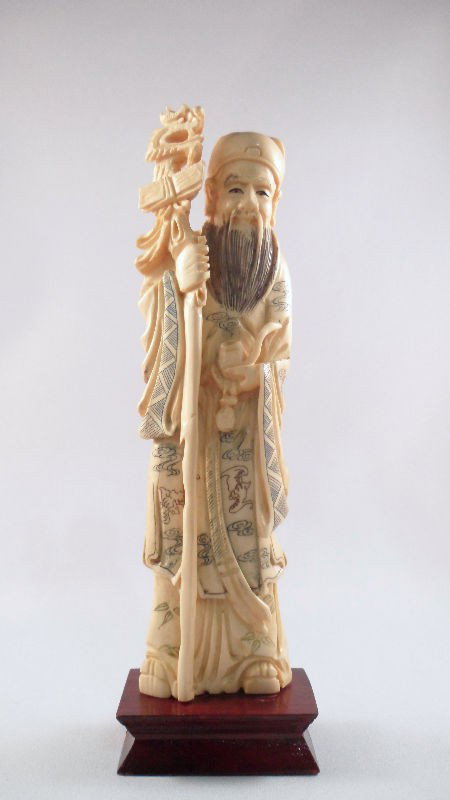 Chinese Ivory Tea-Stained Man with Monkey: Chinese ivory tea-stained figure of a man holding a monkey. Figure holds the monkey in a gentle position as he kneels on the wood base. The piece is decorated with pen work. Measures 6 1/4"H, base mea