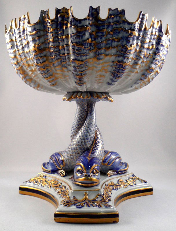 Royal Worcester Porcelain Compote: Royal Worcesester porcelain compote. Beautifully scalloped bowl painted blue with gilt accents. Piece is supported by three intertwined dolphins, which stand atop a plinth. Royal Worcester mark is pre