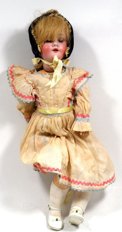 German Antique Girl's Doll: German antique girl's doll. She wears an original ruffled dress and a black bonnet. Her legs are connected by ball-joints. The back of her head is marked "Special/Germany." Please note the dress has b