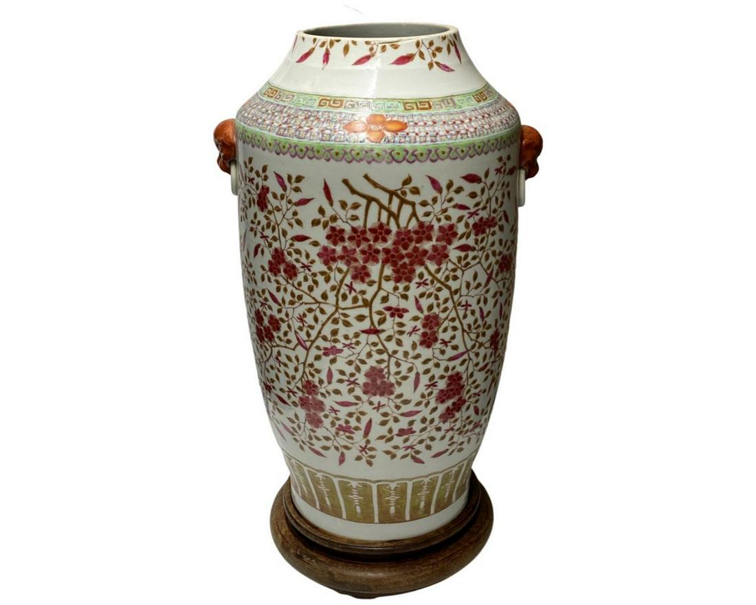 Antique Chinese Famille Rose Porcelain Floral Blooms Vase: Antique Chinese hand painted Famille Rose porcelain vase depicting floral blooms on trees. Completed with rust red figural foo lion handles. Includes fitted wooden display base. Measures approx. 19" h