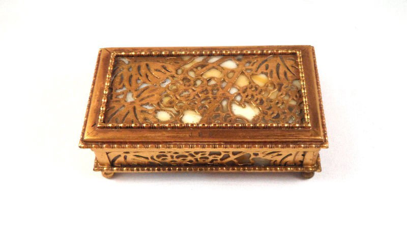 Tiffany Studios "Grapevine" Stamp Box: Tiffany Studios stamp box in the "Grapevine" pattern. The piece is in patenated bronze and caramel slag glass. The piece displays the grapevine pattern and contains a removable bronze stamp holder ins