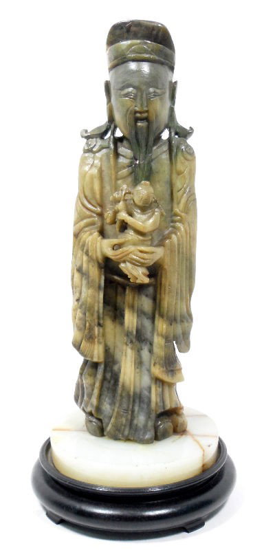Chinese Soapstone Figure of a Wiseman and Child: Chinese soapstone figure of a wise man with a child. The wise man has a long beards and wears draping robes. He holds a small child in his hands. The piece sits atop a hard stone and wood base. Measur
