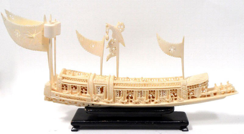Chinese Ivory Carved Boat: Chinese ivory carved boat. This exquisite piece is intricately carved and features miniature figures of people sitting on the top of the boat and in the windows. The window even open, which is an exam