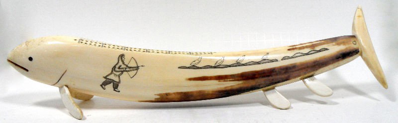 Inuit Ivory Cribbage Set: Inuit ivory cribbage set. The main piece is in the shape of a whale with etched images of a map on one side and a scene of a hunter hunting birds on the other. The peg holes are drilled into the top. 