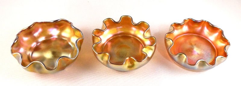Tiffany Studios Favrile Glass Salts (3): Tiffany Studios Favrile Glass Salts with gold iridescense and fluted edges. Marked LCT Favrile, measure 2 1/2" dimaeter. For shipping and required insurance quotes feel free to call Ryan or Dave at Ea
