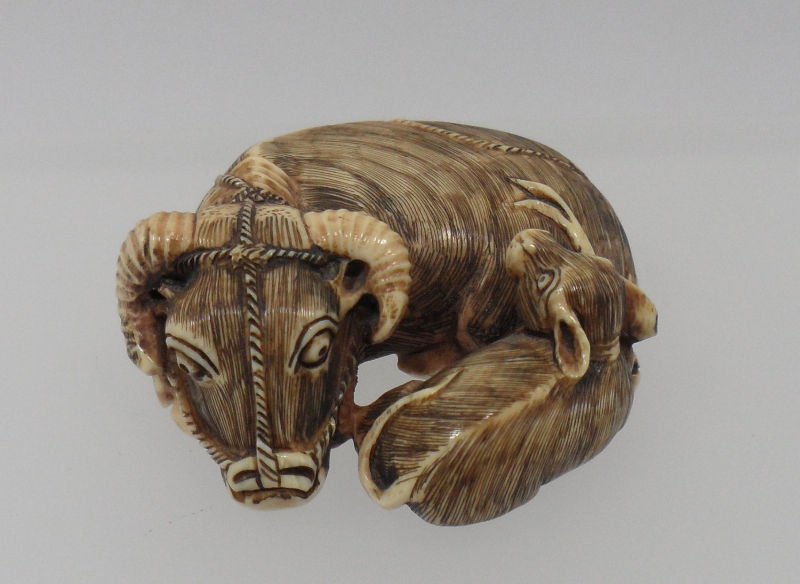 Carved Ivory Ram Netsuke: Carved Ivory Netsuke of a ram nestled with his young. The detailed work on this piece is priceless. Measures approx. 2'' x 2''.For shipping and insurance quotes please call Ryan or Dave at Eagle Shipp