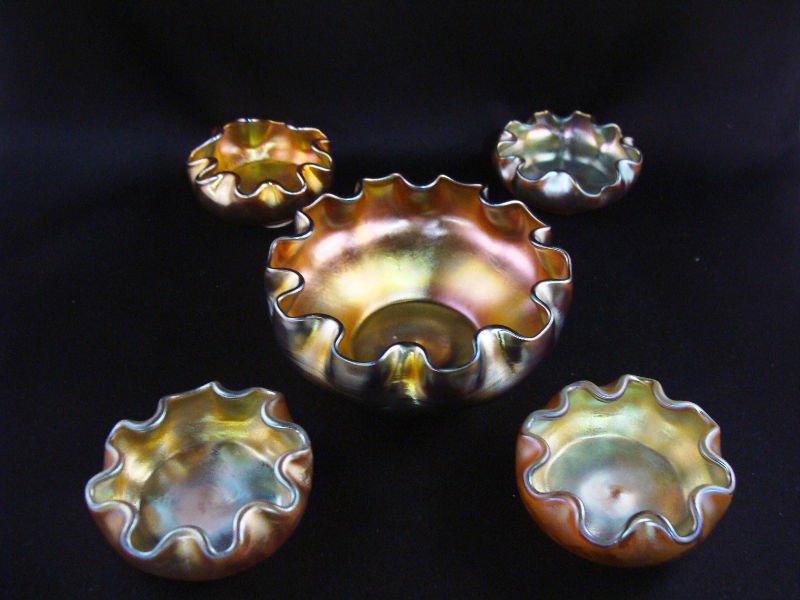 5 L.C.T. Favrille Salt Cellars: 5 L.C. T. Tiffany favrille iridescent salt cellars comprising of 4 individual salts measuring 3/4" high x 2 1/2" diameter and one master salt measuring 1 7/8" high x 4" diameter.For Domestic or Intern