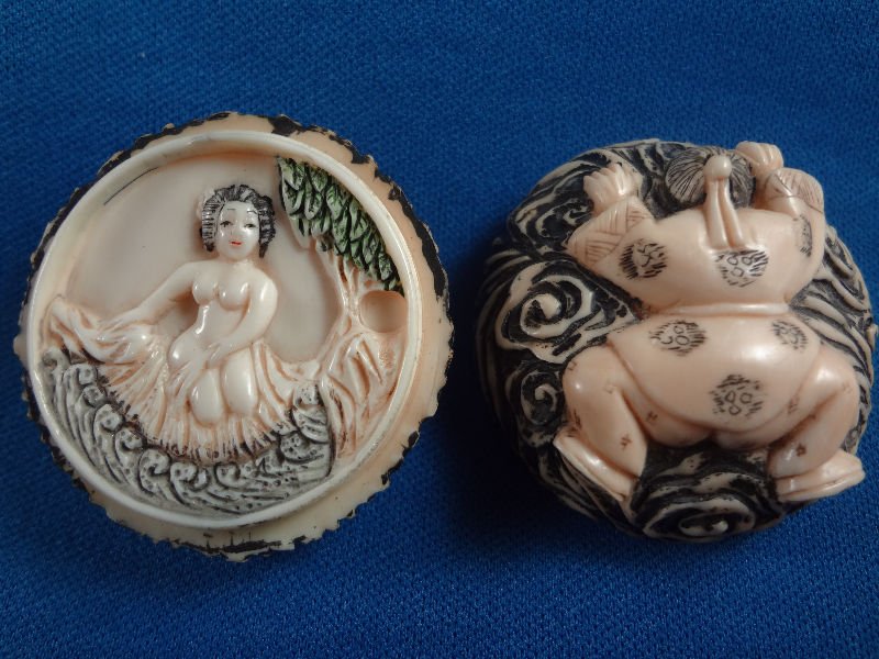 Carved Ivory Netsuke W/Nude Woman Inside: Carved Ivory Netsuke with nude woman inside. The cover has a man laying face down and the inside features a nude woman with polychrome design. Artist signed on the inside top cover. Measures 1" high x