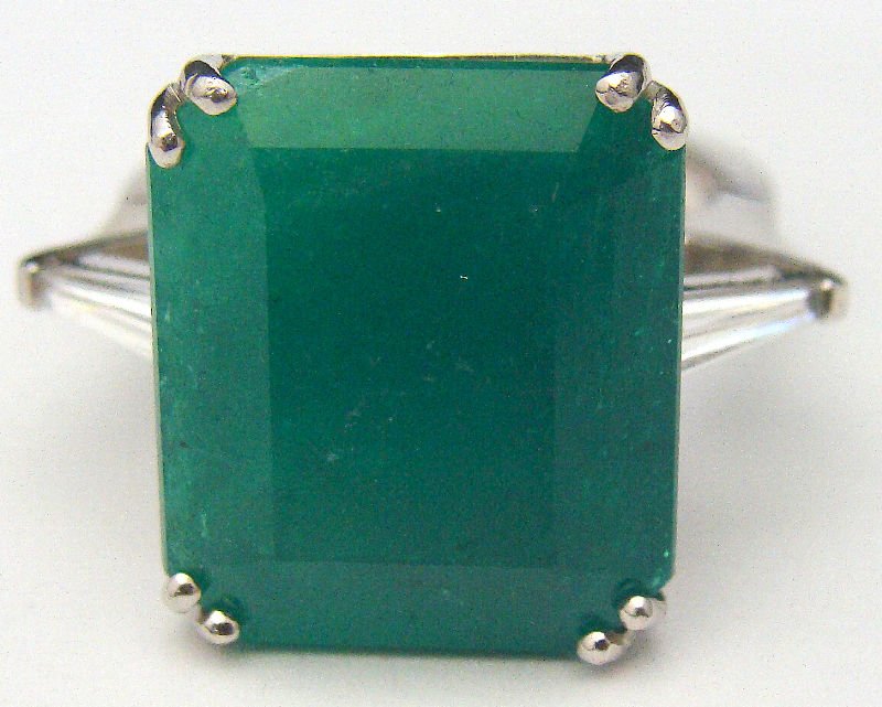 18kt WG Emerald Cut Genuine Green Emerald Ring: 18kt white gold emerald cut genuine green emerald ring flanked by one baguette diamond on each side. Green emerald 13.91ct. Approx. 40ct diamond. Size 7. Weighs 6.0dwt. For Domestic or International S