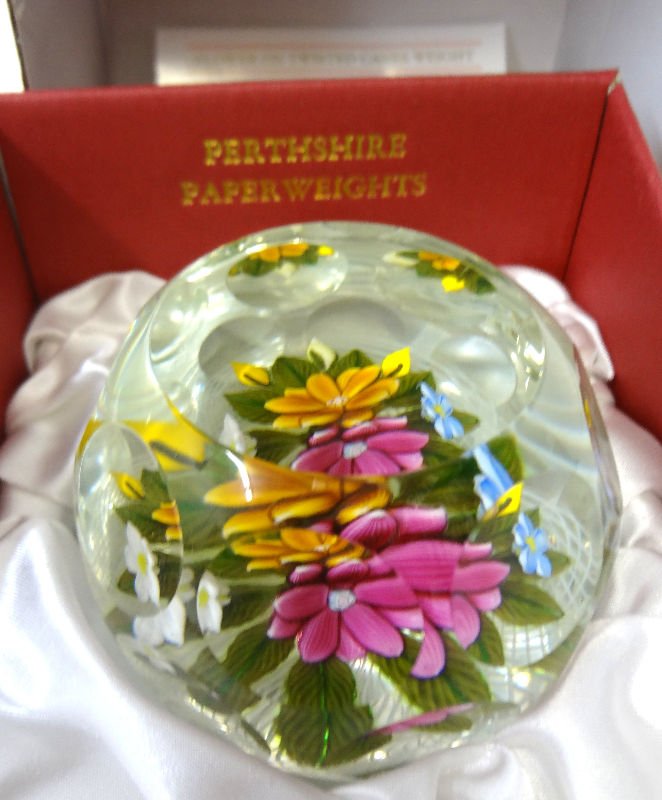 Perthshire Flower on Twisted Canes Paperweight: Flower on Twisted Canes Paperweight. This weight features an unusual base of double twisted canes in ruby, white and blue twists on the inner layer and fine lace on the outer layer complemented by a d