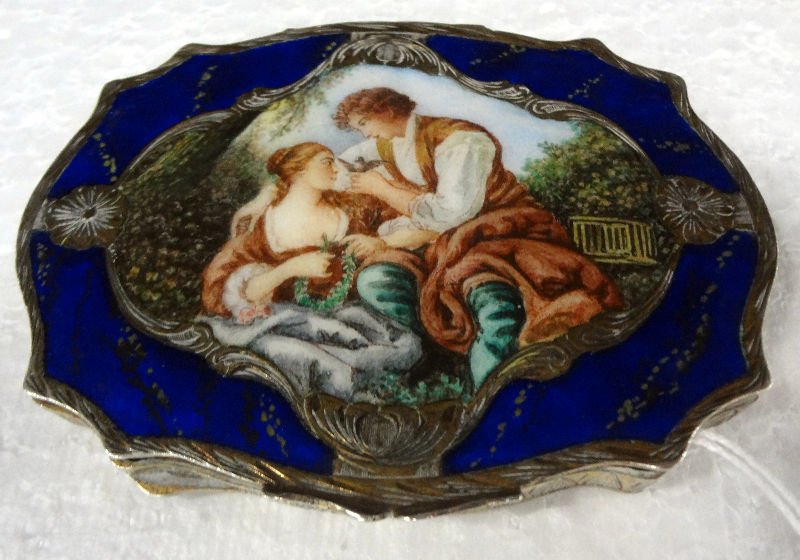 800 Silver Enamel Compact: 800 Silver Enamel Compact. Depicting a romantic scene on lid and scroll work on the other. Measures - 3" high x 3 3/4" wide.For Domestic or International Shipping Quotes Please Feel Call Ryan or Dave 