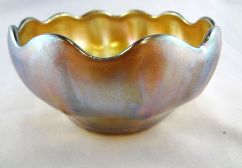 Tiffany L.C.T Favrile Signed Bowl: Tiffany L.C.T Favrile Signed Bowl circa 1900. This bowl is a burnished gold color that emits hues of blue and green. Measures - 2 1/2" high x 4 5/8" diameter.
