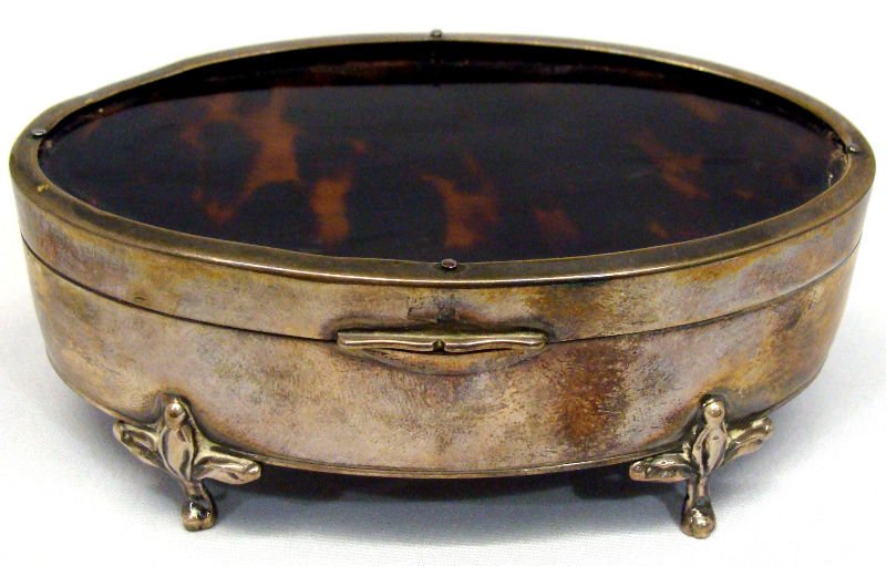 Tortoise Shell & English Silver Box: Tortoise shell and English silver oval hinged covered footed box with key. Measures 1 3/4" high x 4 3/8" long.