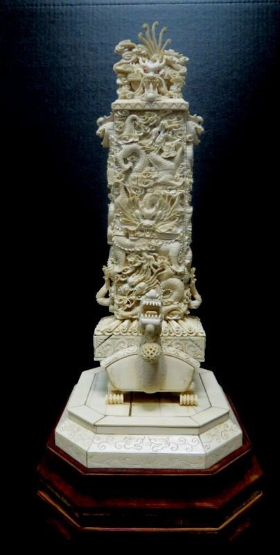Early 20th C. Carved Ivory Dragon's Tower: Early 20th C. Carved Ivory Dragon's Tower, 19" featuring a rectangular obelisk decorated with a repeated interwoven dragon motifs, sitting atop a stylized dragon in a hand carved octagonal base decora