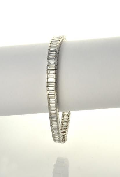 1950's Platinum & Diamond Bracelet: This is a 1950's platinum and diamond bracelet. The bracelet features a graduating straight line design that is channel set with 77 baguette cut diamonds that weigh approximately 18.00cts. They ar