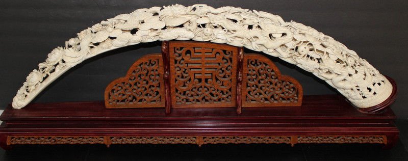 Massive Chinese Carved Ivory Imperial Dragon Tusk: Massive Chinese Carved Ivory Imperial Dragon Tusk. Ivory tusk - 42 1/2" long, approx. - 4 1/2" diameter. Overall with base - 16 1/2" high x 45" long. Tusk approx. - 10 pounds. Please Contact - Tom at 