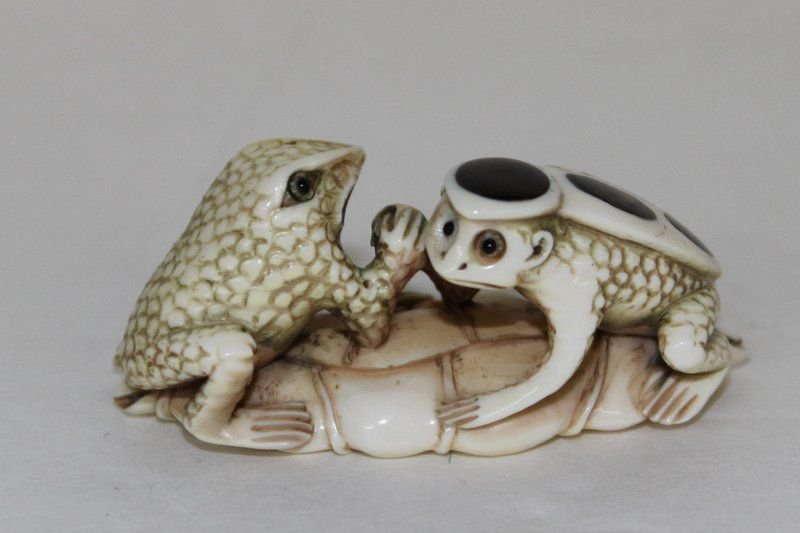 Japanese Polychrome Carved Ivory Netsuke: Rare Japanese Polychrome Carved Ivory Netsuke, depicting a frog and a tortoise (tortoise has actual tortoise shell spots on its shell) arm wrestling. Measures - 1" high x 2 1/4" long. Weighs - 13.6 g.