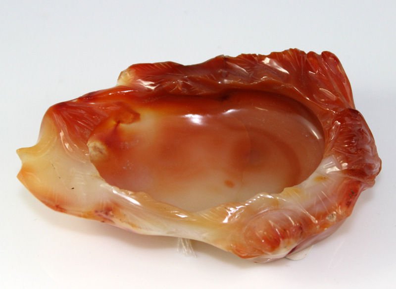 Chinese Carnelian Brushwasher: 20th Century Chinese Carnelian Brushwasher. Of flattened oval form, with short upright sides, carved in low relief with flower blossoms; the attractive stone of deep orange and buff color. Measures - 