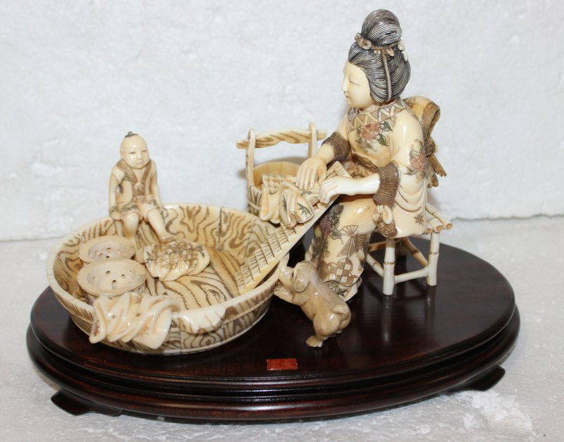 Chinese Carved Hippo Ivory Group: Chinese Carved Hippo Ivory Group. 7 3/8" high x 10" wide. Depicting mother and child doing laundry. Mounted on wooden base. THIS LOT IS THIRD QUARTER 20TH CENTURY, OR EARLIER ORIGIN. INTERNATIONAL CLI