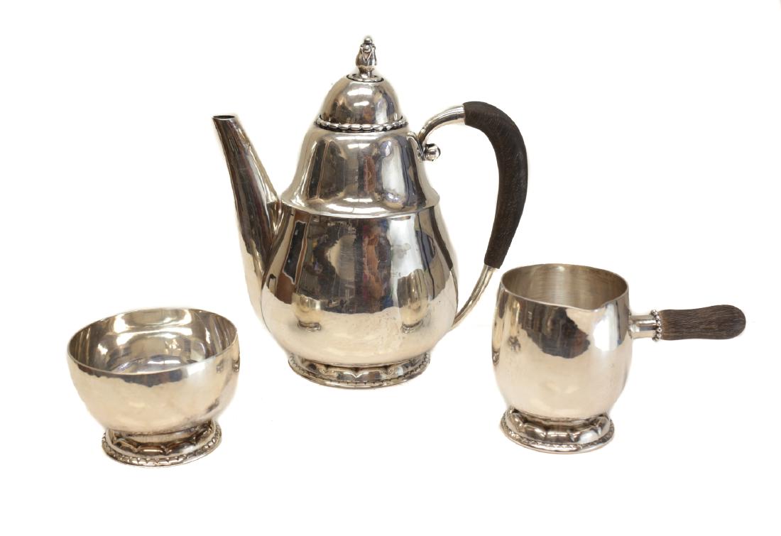 Georg Jensen Sterling Silver Chocolate Set: A fine 3 piece Mocha service Georg Jensen sterling silver tea set , model 34A, circa 1925. Teapot and creamer with wood handles. GI mark and crown mark. Weight: 19.5ozt Measures: creamer 3 inches tal