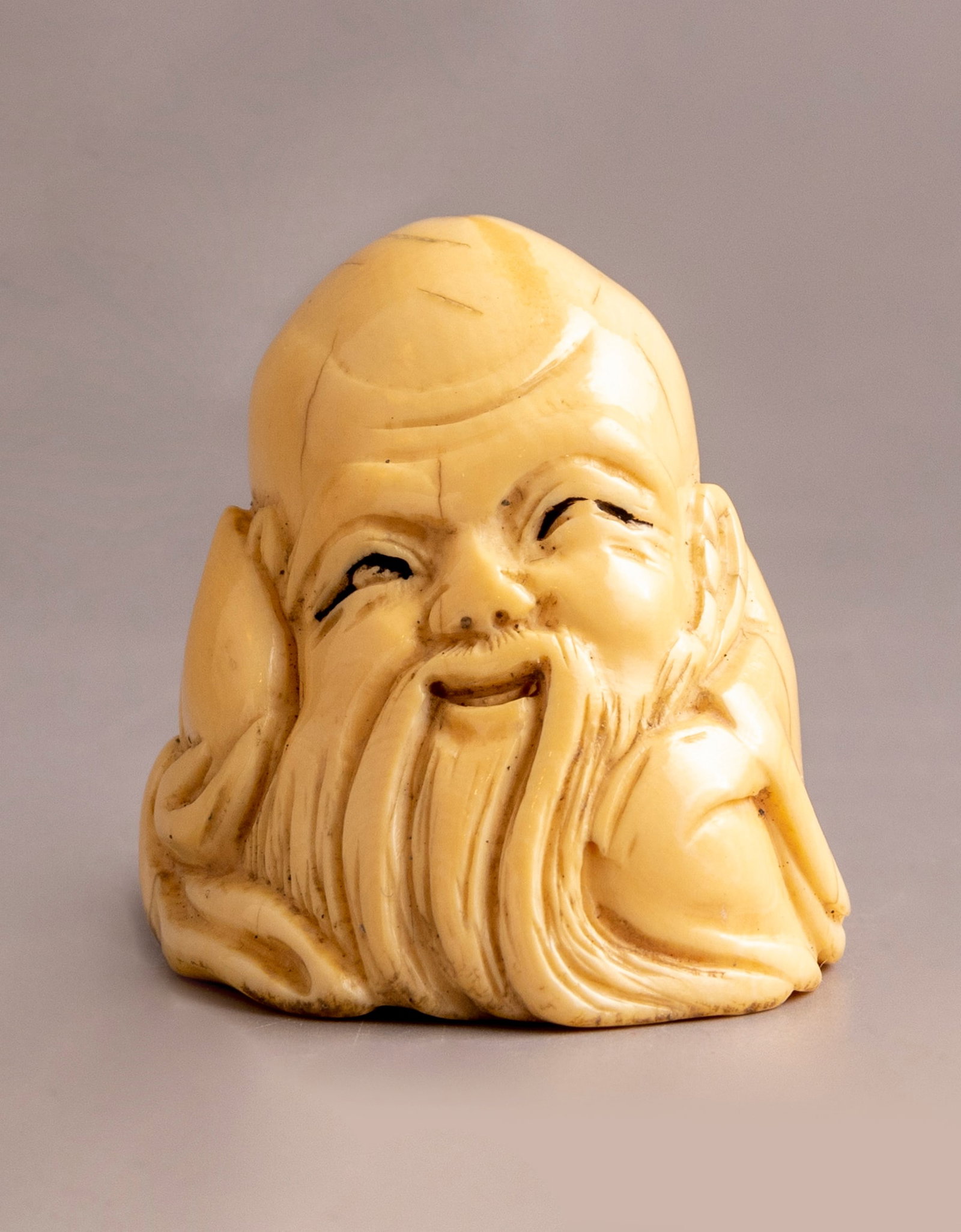 Japanese Carved Netsuke: Japanese Netsuke, carved in the form of Buddha's head. Height: 3.5 cm. Signed. Cracks.
