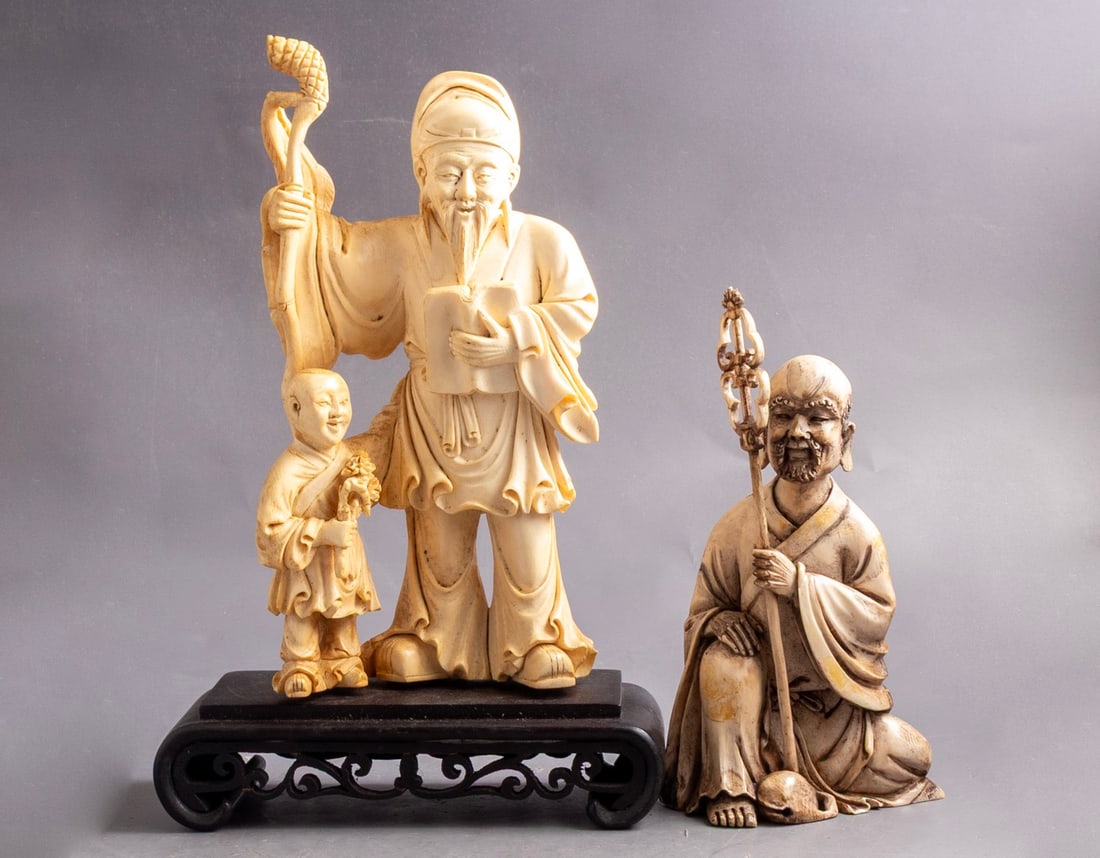 Japanese Carved Okimonos: Lot of two Japanese carved okimonos, one depicting a teacher and a student on a wooden base, the other of a man with a wand. Height (including base): 17-21 cm. One signed.