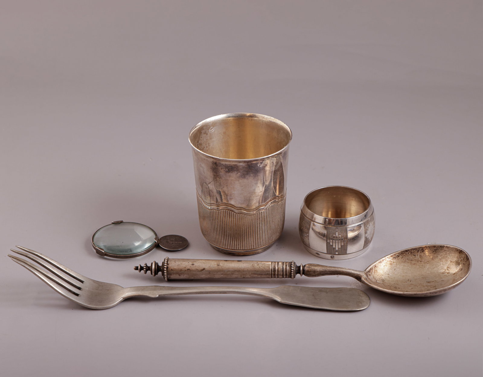 Silver Items, Various Origins: Lot of 800 and 84 silver items, various origins. Including a cup, spoon, fork, napkin ring, and additionally a magnifying glass by Tiffany & Co. Length: 6–21.5 cm. Total weight (without the