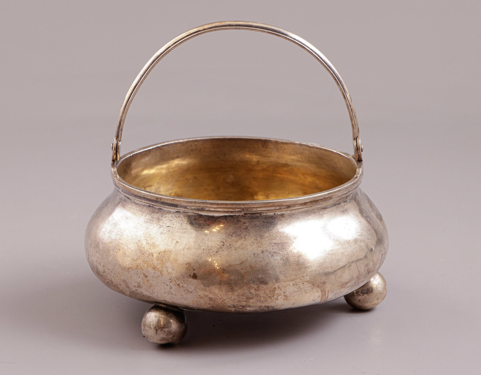 Russian Silver Bowl: Russian 84 silver bowl, stands on three legs. With a carrying handle. Height (including handle): 11 cm. Weight: 161 grams. Hallmarked. Minor flaws.