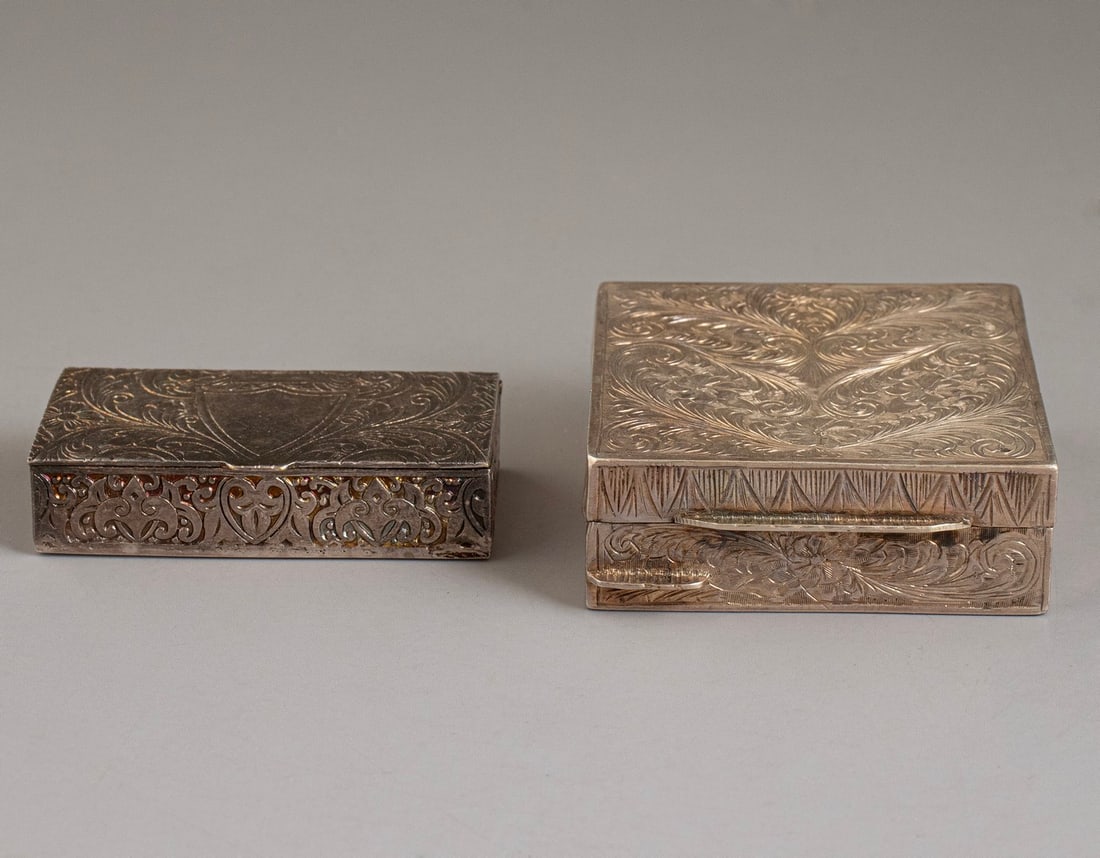 Silver Tobacco Boxes: Pair of silver tobacco boxes, decorated with engraved work. Length: 5.5 cm. Total weight: 78 grams. Unsigned, silver tested.