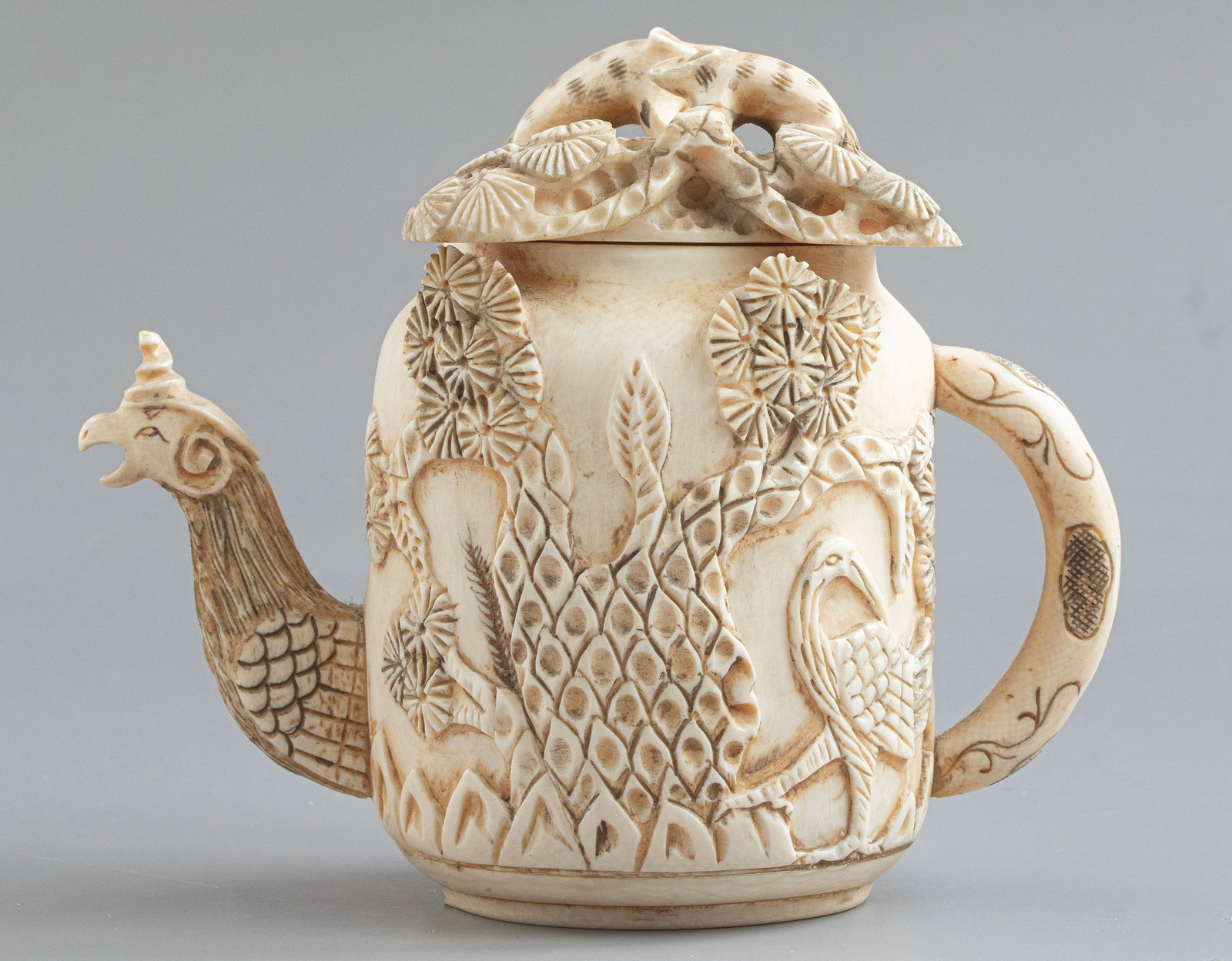 Carved Chinese Kettle: Chinese carving in the form of a teapot. Decorated with animals and floral motifs, the spout formed as a phoenix head. Height: 10 cm. Signed.