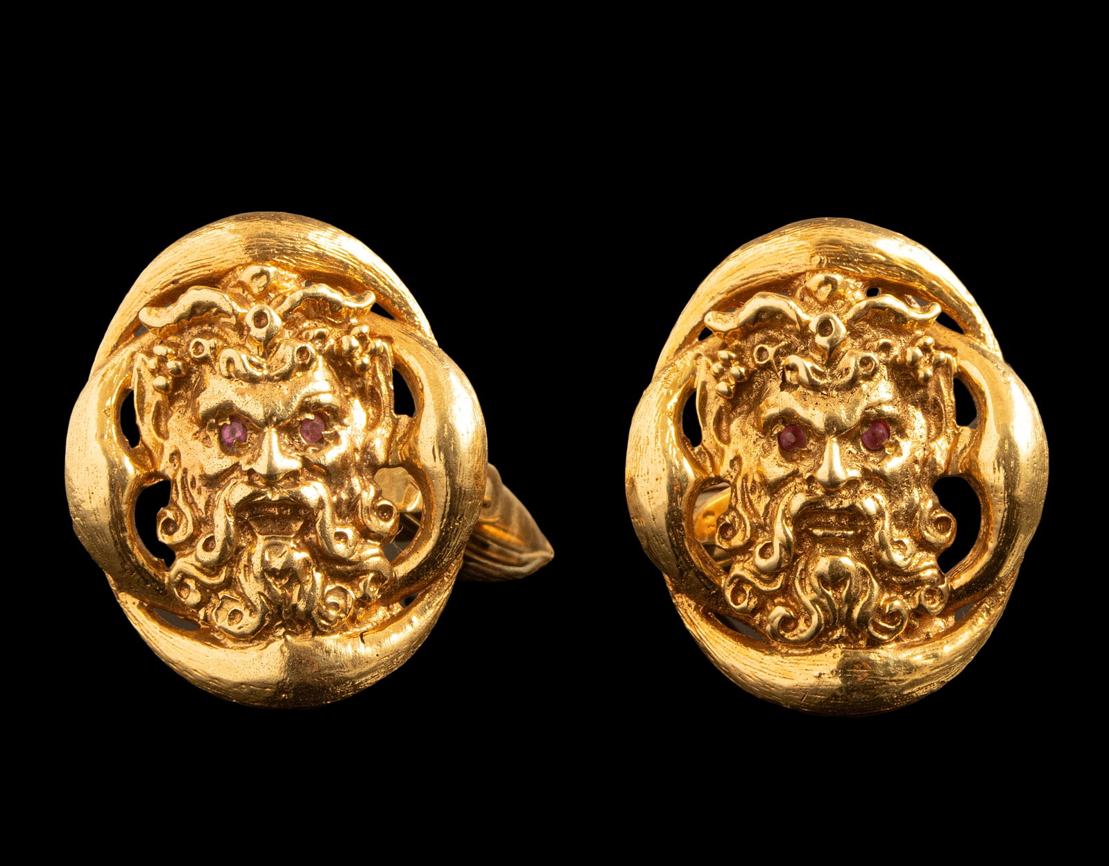 Gold Cufflinks: Pair of 14K gold cufflinks, decorated with the figure of Zeus, the eyes are set with ruby. Length: 23 mm. Weight: 21.3 g. Hallmarked.