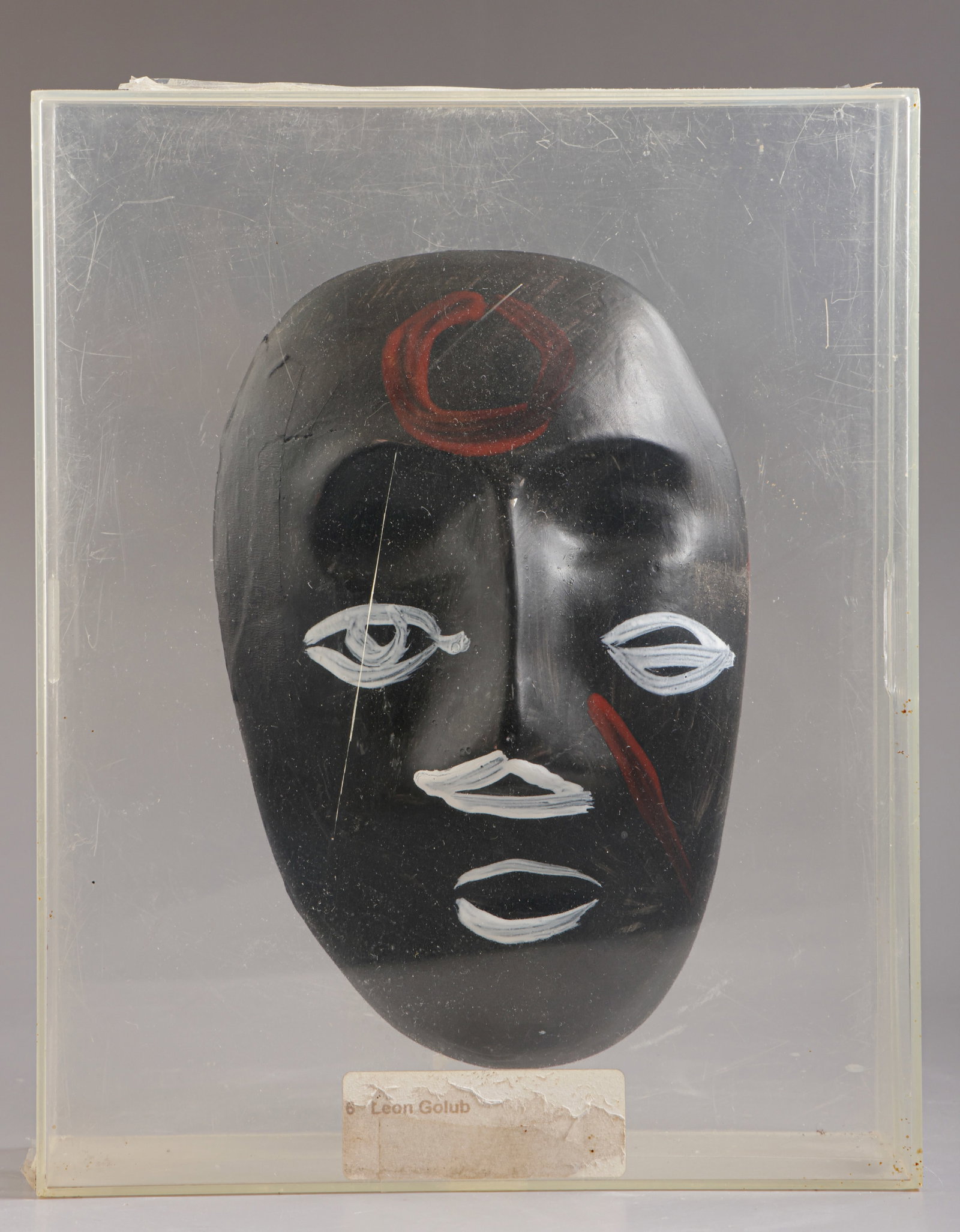 Leon Golub (American, 1922-2004): Leon Golub (1922–2004), Mask, hand-painted plaster, housed in a plexiglass frame, mask height: 21 cm, signed. Provenance: Sotheby’s, New york, December 8, 1996, Lot No. 6A. Spaicial auctio