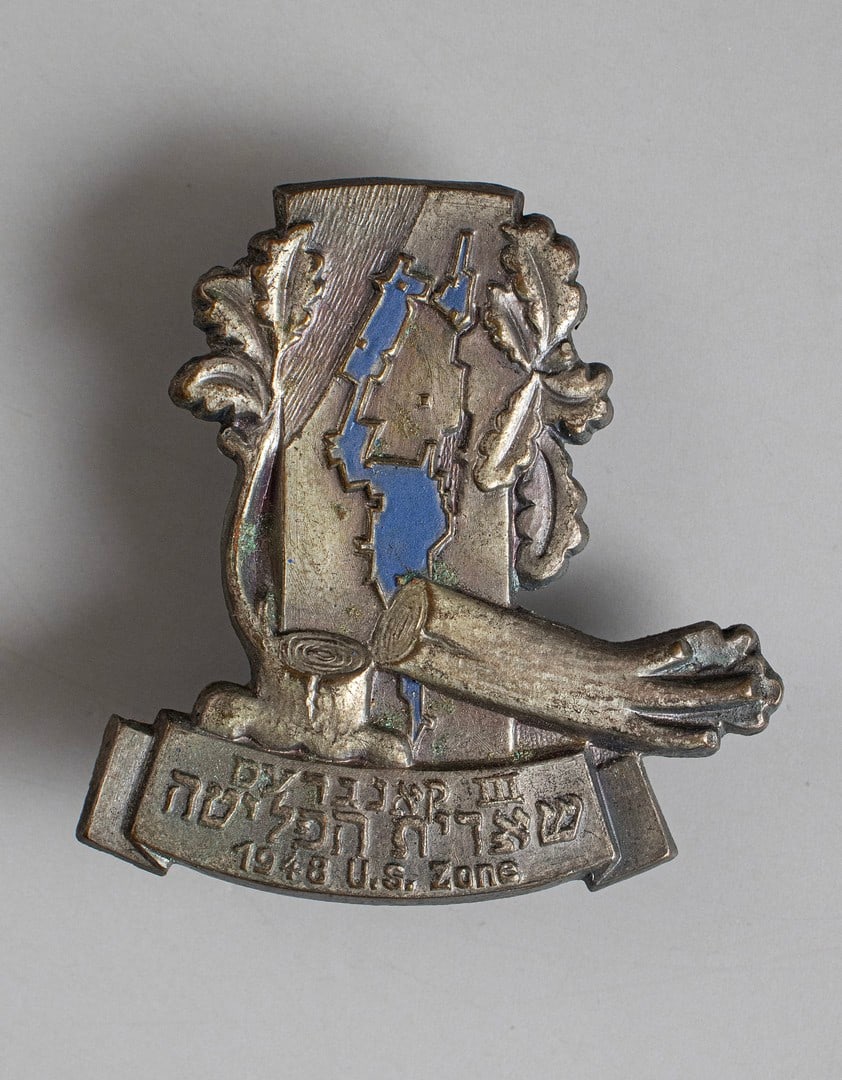 Emblem of the Third Congress of She'erit Hapleta, 1948: Metal pin commemorating the Third Congress of She'erit Hapleta in the American Zone of Germany, 1948. With a relief of a fallen tree and a map of Eretz Israel according to the UN Partition Plan for