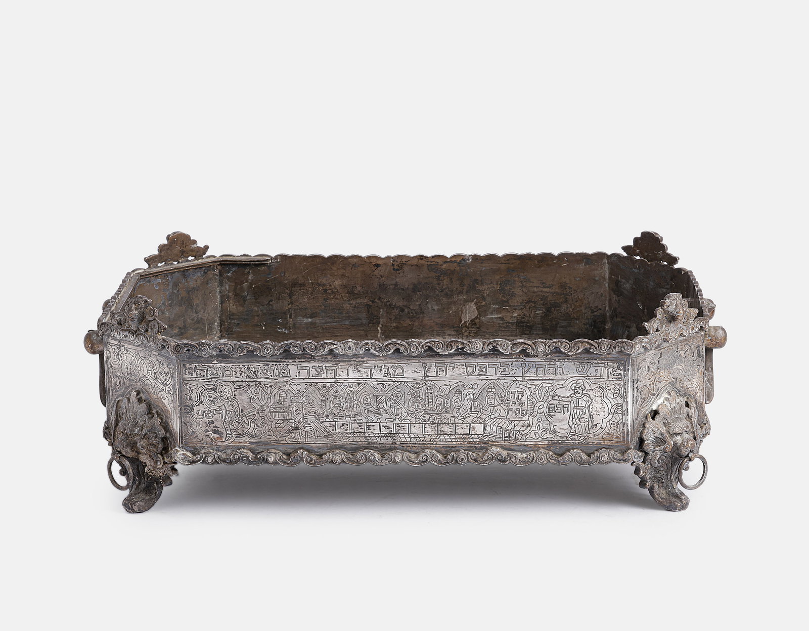 Large Silver Passover Bowl, Iraq: Judaica - Large and unusual silver Passover tray, probably Iraq. Stands on four lion-shaped legs with rings in their mouths, surmounted at each corner by lionesses. With two carrying handles. The side