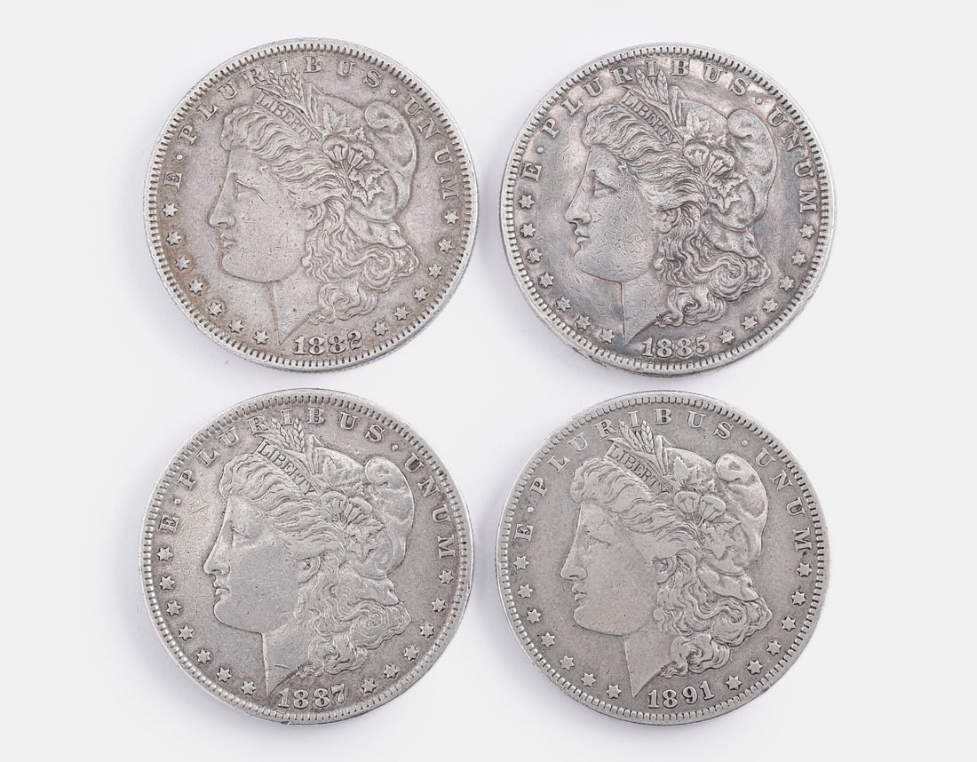 American Silver Morgan Dollar Coins: Lot of 4 American silver Morgan Dollar coins. Total weight: 106 grams. Various dates, mints, and conditions.
