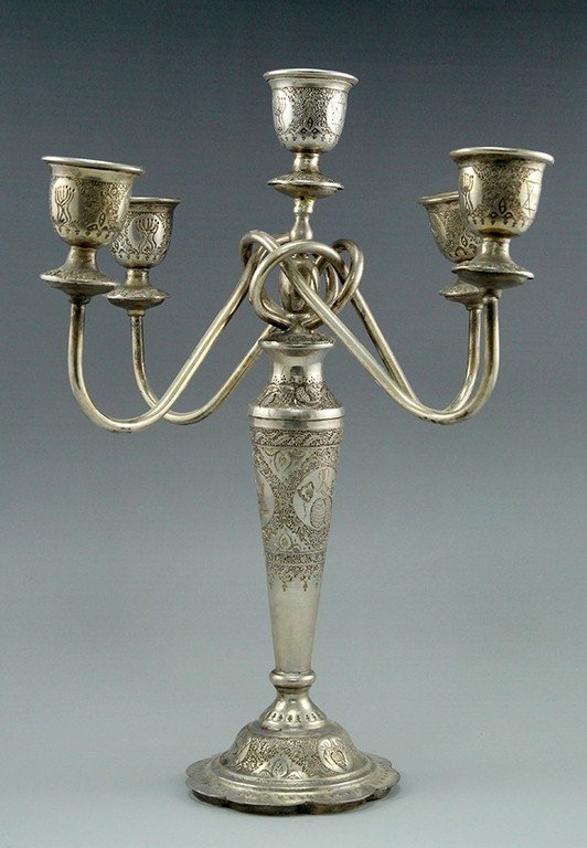 Judeo-Persian silver candelabra: A Judeo-Persian five branched candelabra, made of silver. Hand hammered and decorated with engravings of Jewish motifs (Menorahs, Star of David). Height: 38 cm. Weight: 1266 grams. Signed on base. Min
