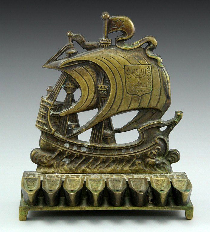 Israeli Hanukkah Menorah: An Israeli brass Hanukkah Menorah shaped as a sail boat with the emblem of the State of Israel and a Hebrew inscription. Width: 13 cm.