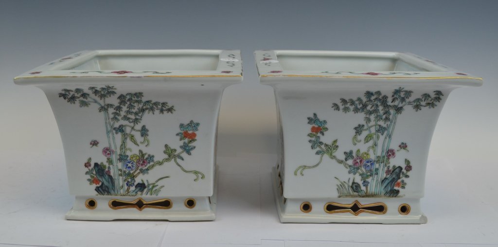 Pair of Famille Rose Porcelain Flower Pots: A pair of famille rose flower pots that have a flower painted on each side. Near the bottom, holes have been carved out and lined with gold gilt. The center of the pot contains a hole for draining wat