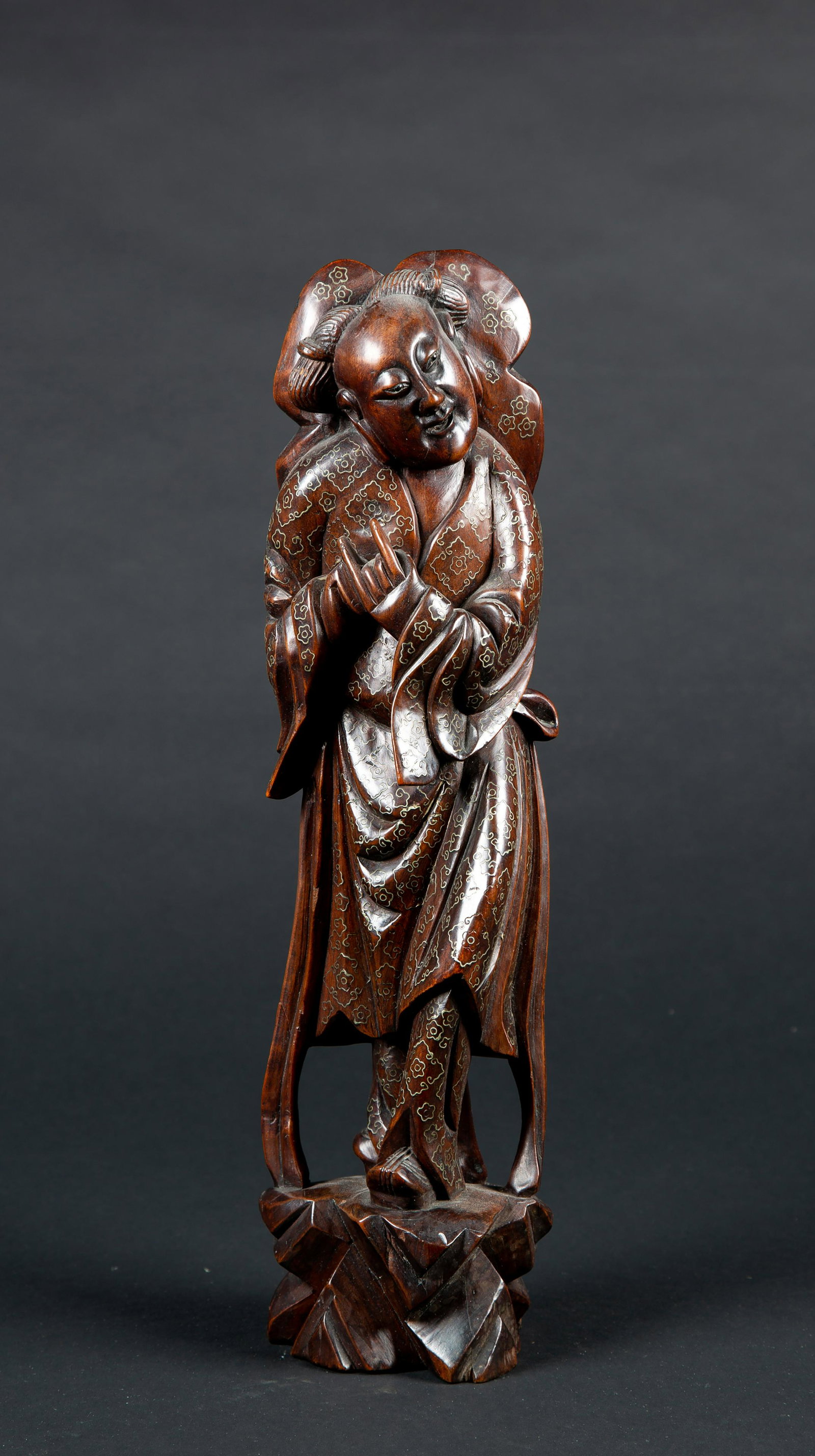 Japanese E20thC Inlaid Figural Wood Carving: Japanese E20thC Inlaid Figural Wood Carving, The 16" tall figure of a robed man standing with a large leaf shaped hat on his back, all over metal (pewter or silver) inlaid floral designs on the back a