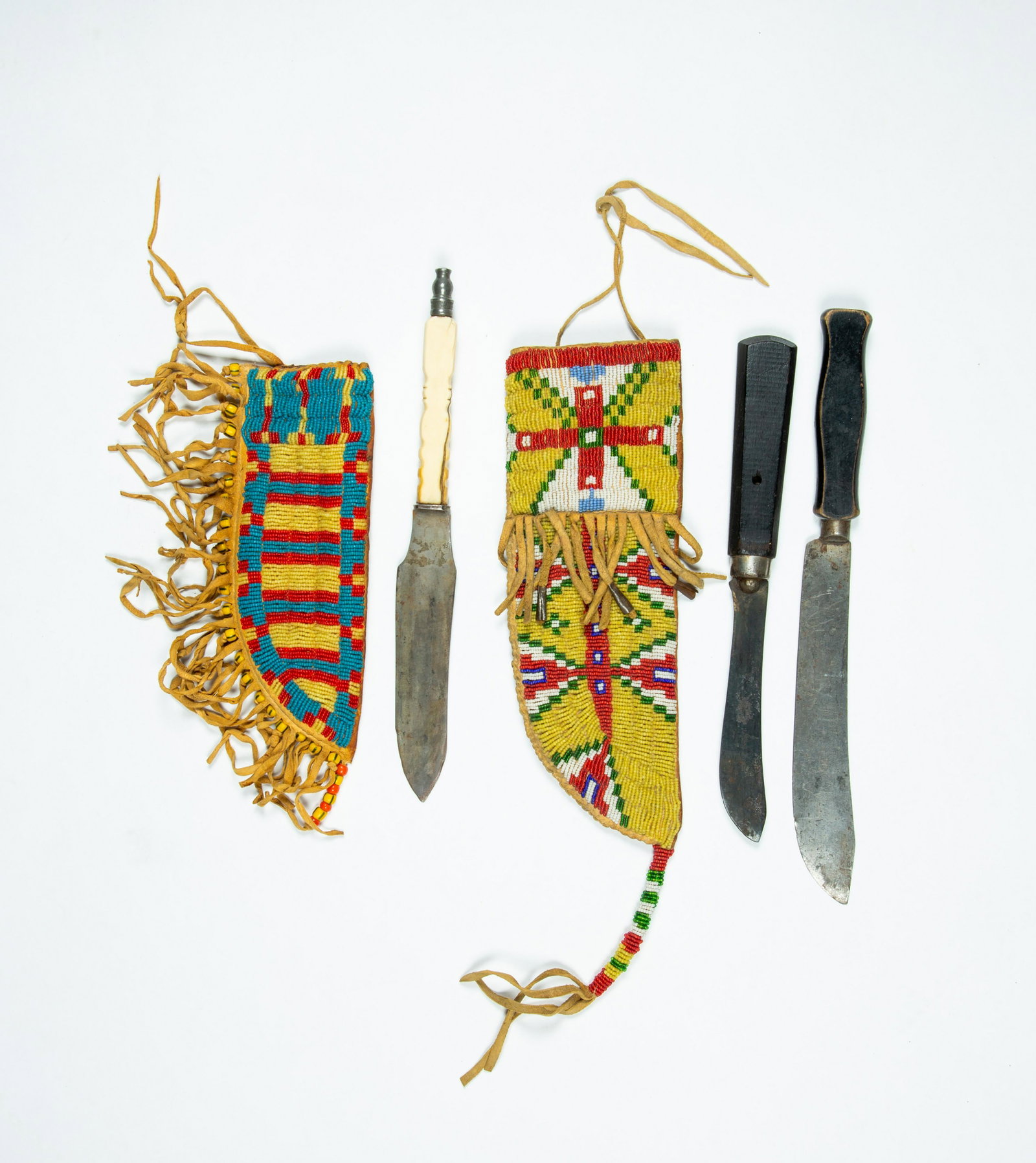 Two Native American Beaded Knife Sheaths: Two Native American Beaded Knife Sheaths, A) A 10 1/4" long sheath with 4" long beaded tassel end, having a multi colored geometric beaded covering to the top side, comes with two old knives, not orig