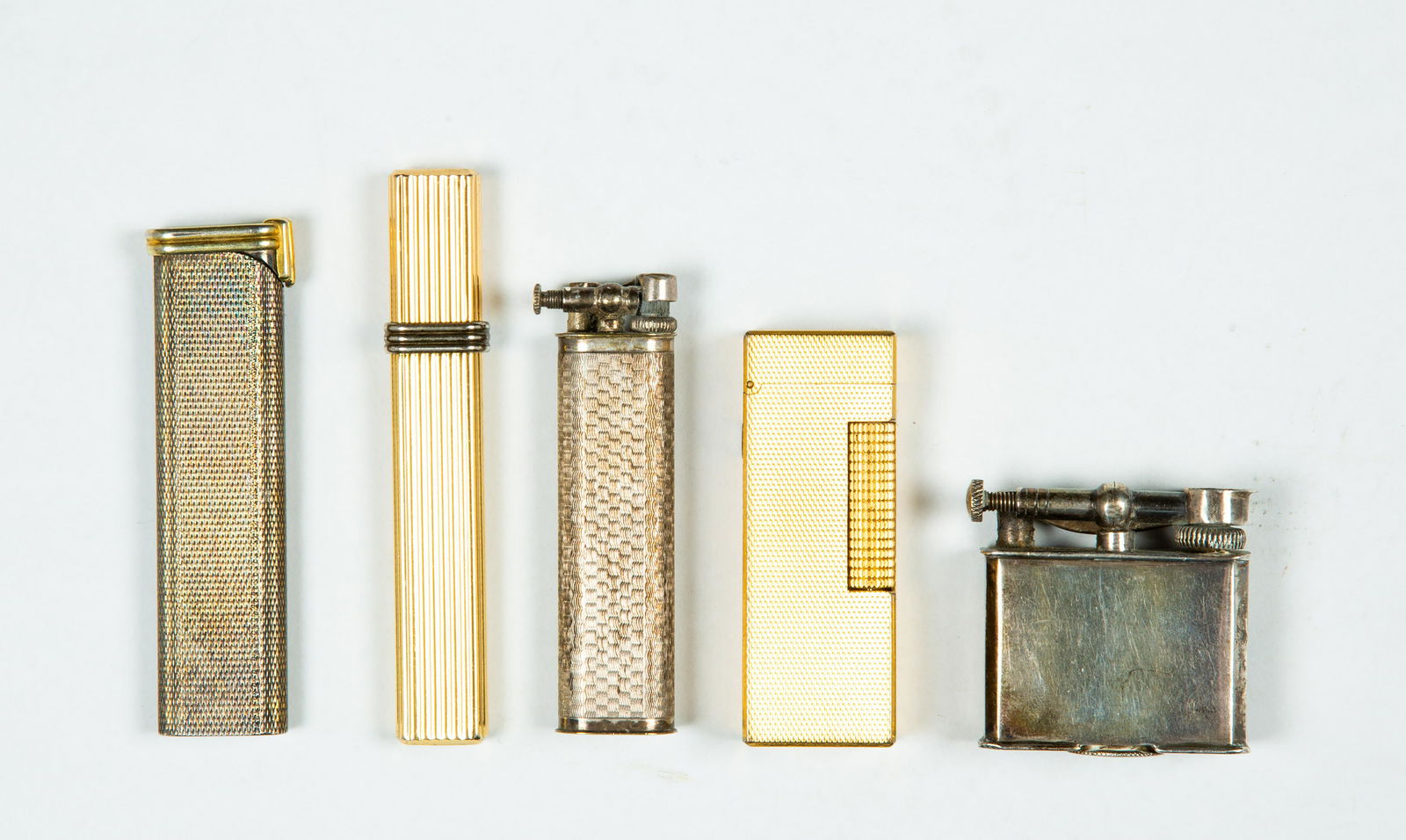Five Vintage Cigarette Lighters: Five Vintage Cigarette Lighters, A) Dunhill gold plated lighter, made in Switzerland, US RE24163, 2 1/2" tall x 1" wide x 1/2" deep. B) Dunhill silver lighter "SYLPH", 2 3/4" tall x 7/8" wide x 3/8" d