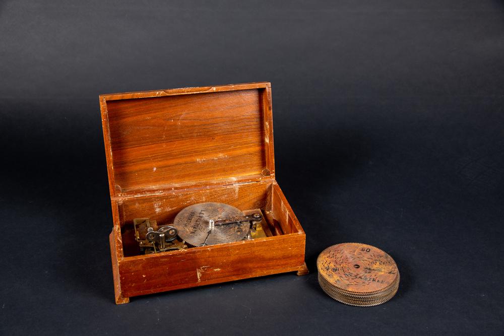 Music Box "Made in Switzerland": Music Box "Made in Switzerland", Marked on movement, a simple wooden box opens to reveal moveable discs (elven in all), working but needs oil, probably E20thC. Estimate: $100 - $200