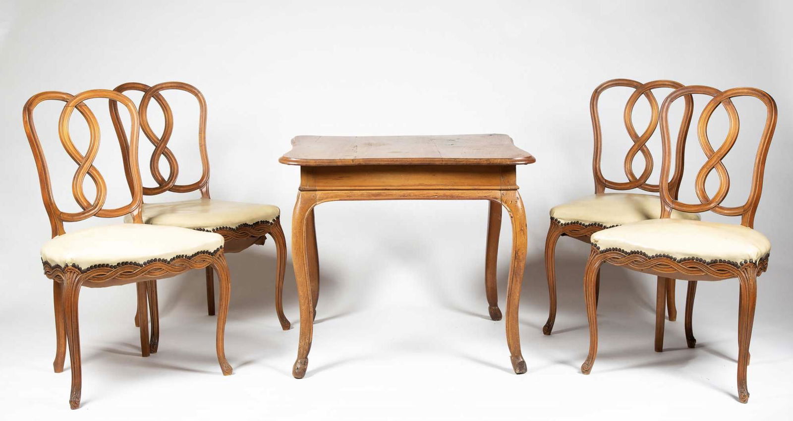 Country French Table and Four Chairs: Country French Table and Four Chairs, The fruitwood table with pegged construction, a shaped top over the base with conforming shape, cabriole legs ending in stylized hoof feet (one foot repaired) pro