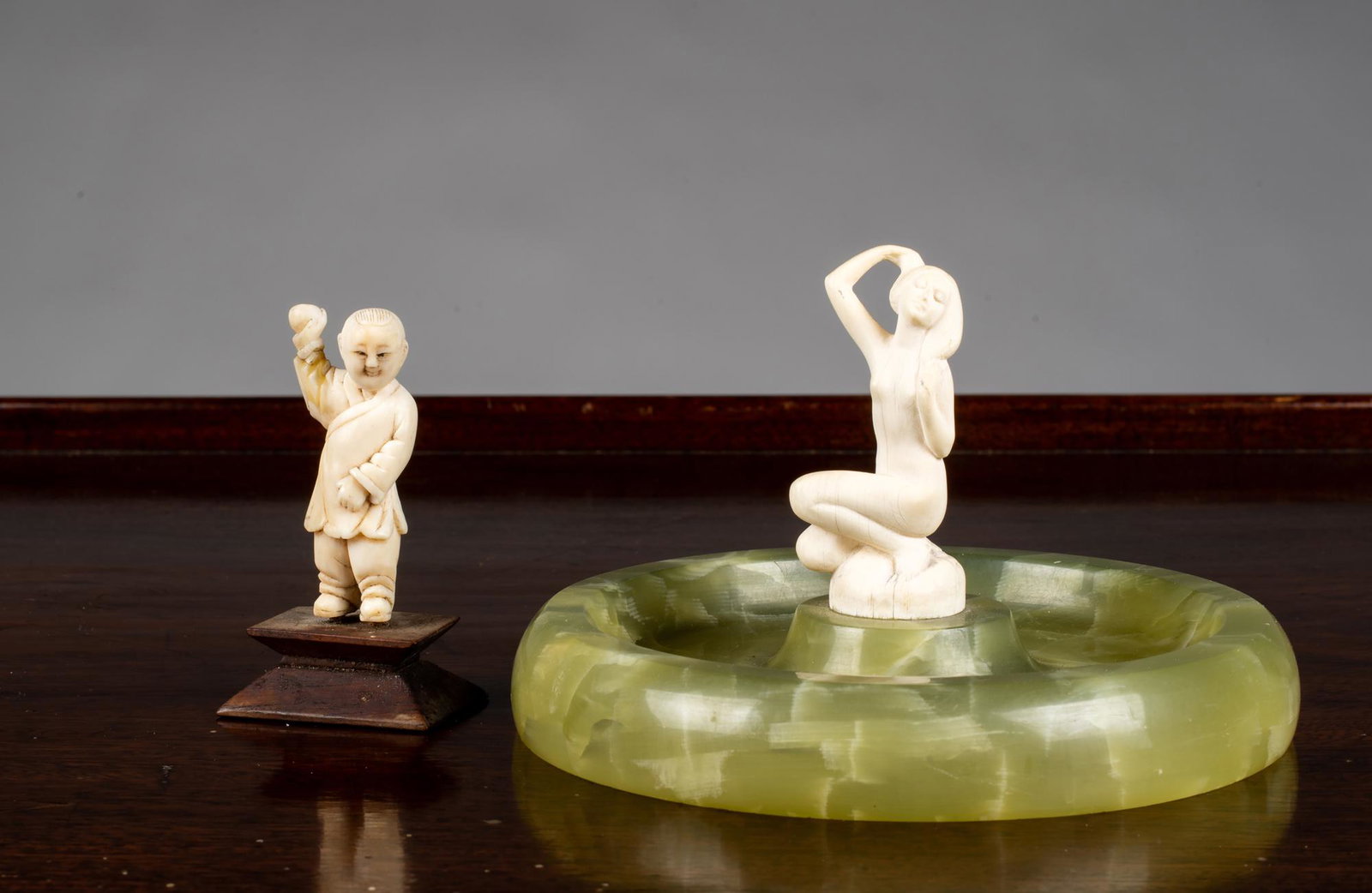 Two E20thC Carved Bone Figures: Two E20thC Carved Bone Figures, A) A 2" tall Chinese boy holding a ball set on a wooden base 2 1/2" tall overall. B) A kneeling nude girl set on a green marble base simulating a pool, 5" diameter x 2 