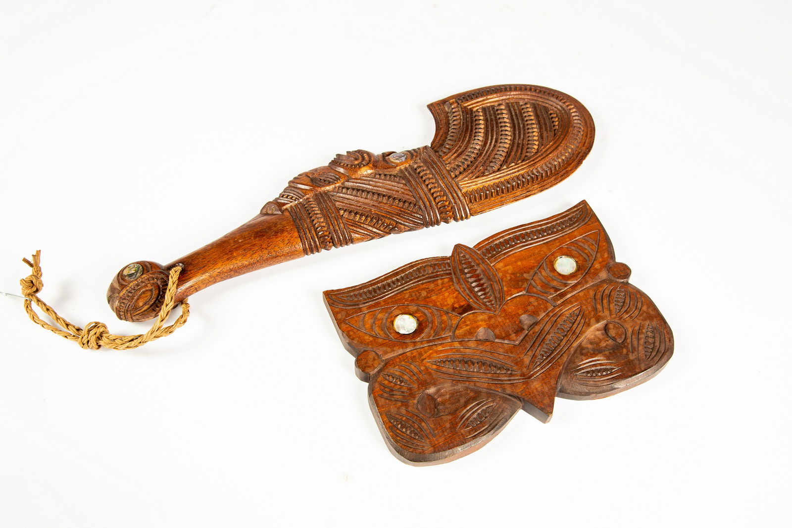 Two Maori Decorative Objects: Two Maori Decorative Objects, A) A patou with four round mother of pearl inlays, length: 15". B) Decorative carved plaque with mother of pearl inlaid eyes, width: 8". Provenance: Irv Fischer Collectio