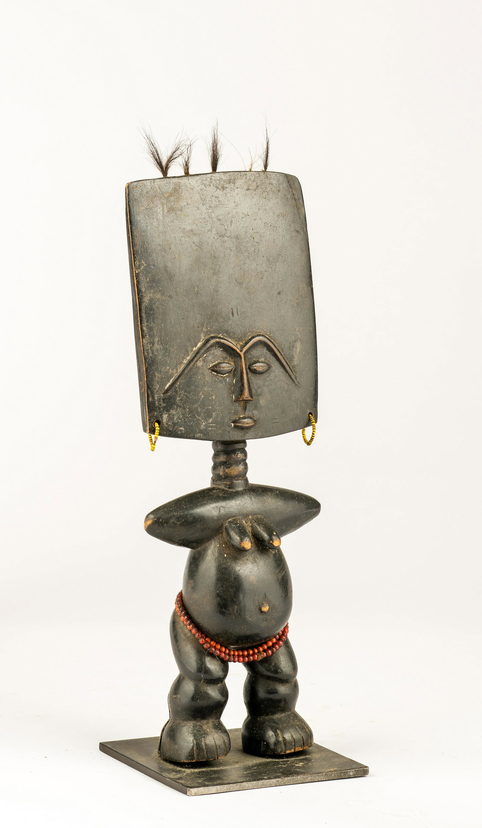 An Akan Akuaba Fertility Figure, Ghana: An Akan Akuaba Fertility Figure, Ghana, with broad flat head, tufts of hair along top ridge, raised facial features above a stout body with conical indications of arms and breasts; beadwork earrings a