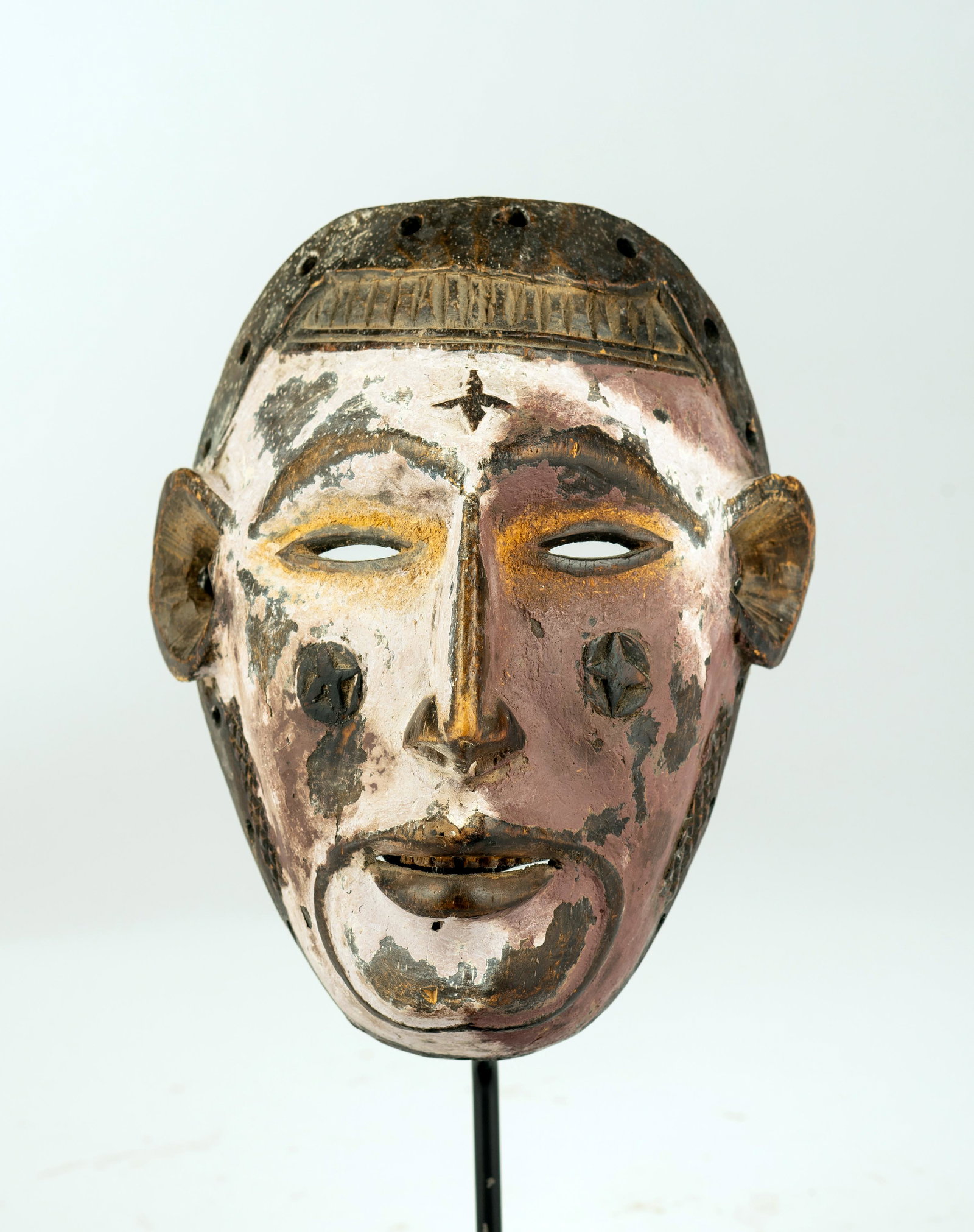 An Ibo/Igbo Mask, Nigeria: An Ibo/Igbo Mask, Nigeria, with remains of old paint, classical scarification, indication of a beard, naturalistic mouth. On custom base, height: 7 3/4". Provenance: Irv Fischer Collection, Michigan