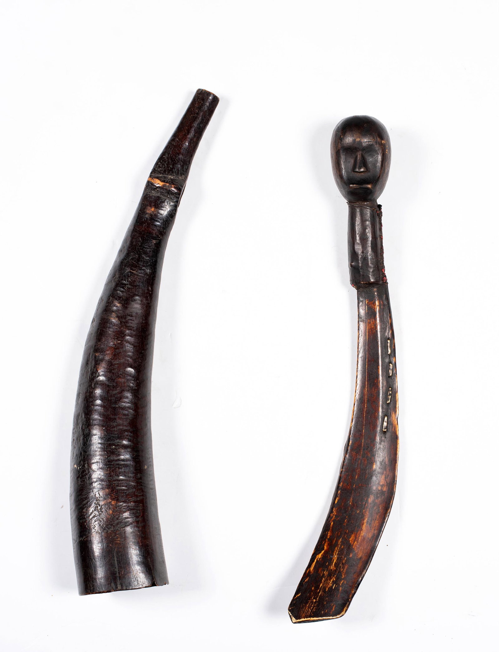 Two Early African Carved Items, A) A carved bone/rib with the handle end being a double side head: Two Early African Carved Items, A) A carved bone/rib with the handle end being a double side head carved out of wood with a sewn leather neck joint, 10 1/2" long, old color. B) A carved horn musical i