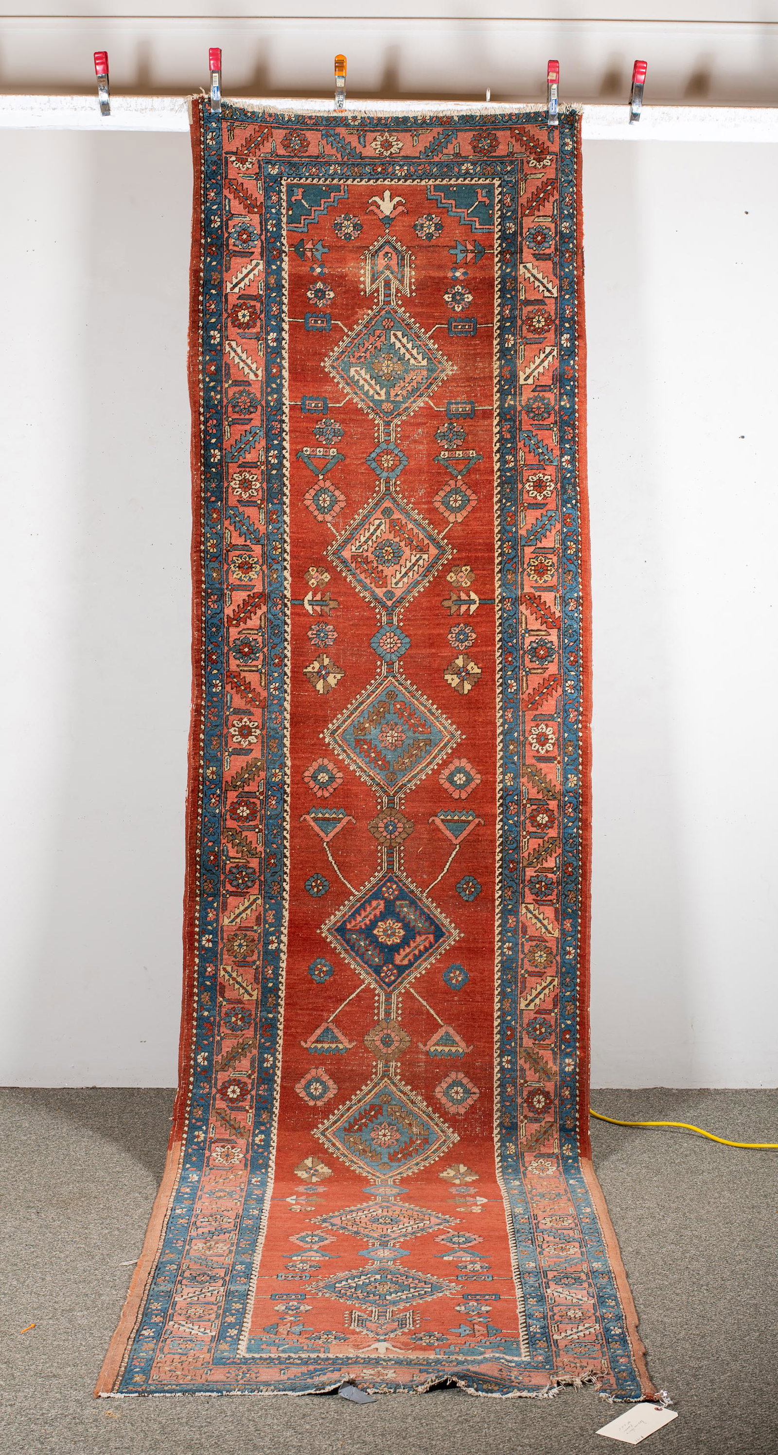 Persian Heriz Oriental Rug Runner, Having multiple connected medallions on a red ground with: Persian Heriz Oriental Rug Runner, Having multiple connected medallions on a red ground with multiple geometric borders, 13'3" x 40" wide, some light wear and losses at each end.
