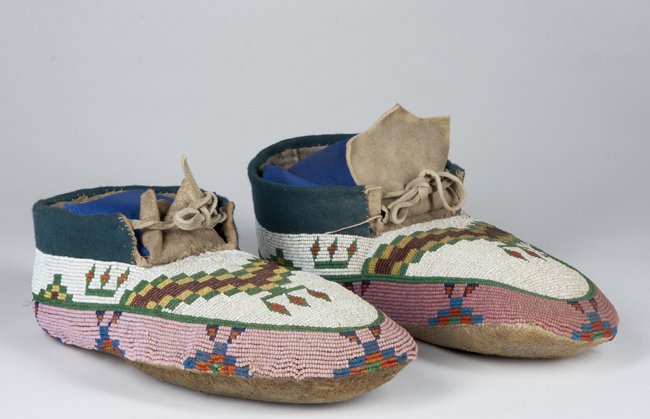 Native American Beaded Moccasins: Native American Beaded Moccasins, overall geometric bead designs on a white ground with pink lower edge, cloth and hide ankle tied, 9 1/2" long, appears to be Early 20th Century.
